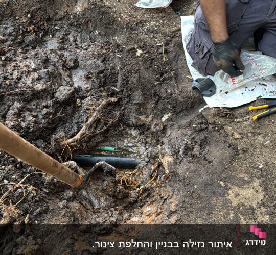 אדם חופר באדמה עם כלי עבודה וצינור חשוף